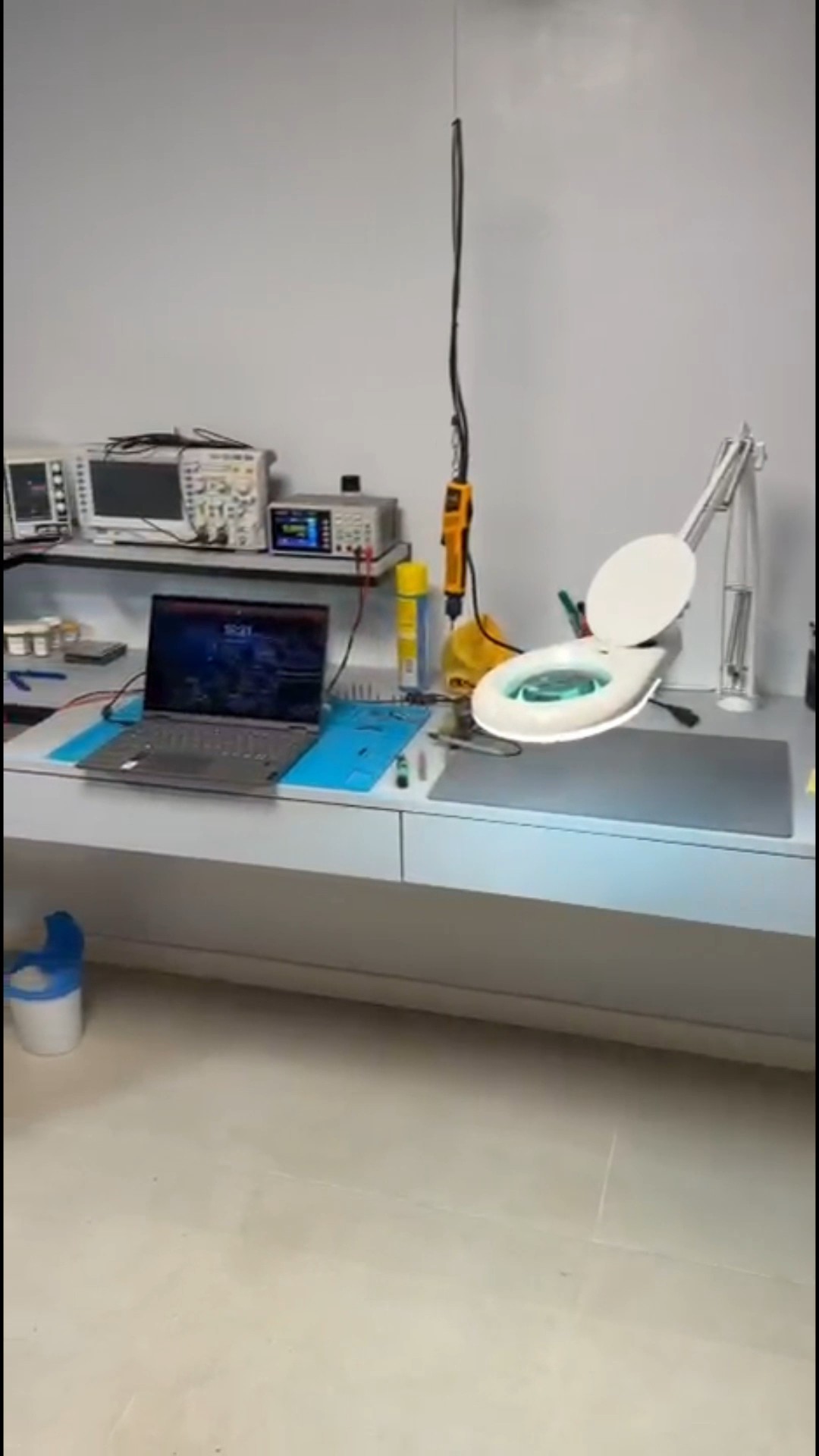 Banco de trabajo con lupa, pistola de calor y notebook